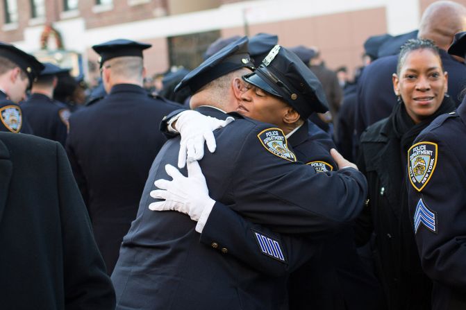 NYPD officers embrace before the funeral of the slain officer.