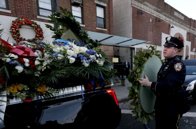 An NYPD officer loads flowers onto a vehicle outside Officer Ramos' funeral.