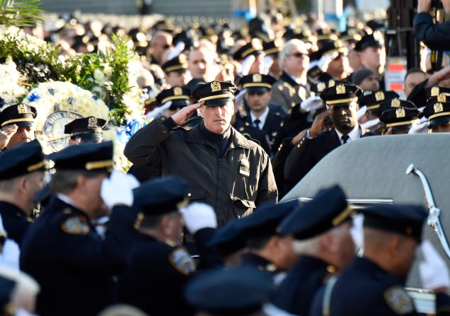Police officers salute as the casket of Officer Rafael Ramos arrives before the funeral.