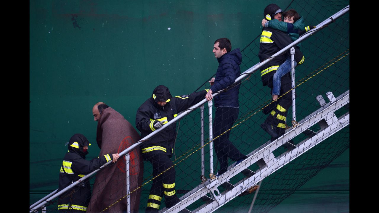 Survivors of the ferry fire are helped by rescuers as they disembark from a rescue ship in the Bari harbor in Italy on December 29.