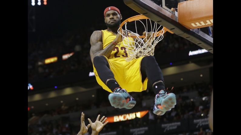 Cleveland's LeBron James hangs onto the rim after dunking the ball Thursday, December 25, in Miami. James was called for a technical foul on the play, and his Cavaliers would go on to lose 101-91 to the Miami Heat. It was James' first game in Miami since he left the Heat in the offseason.