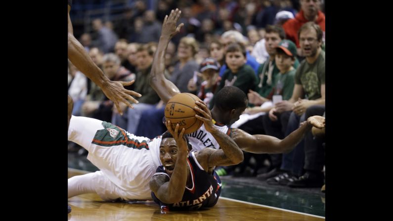 Jeff Teague of the Atlanta Hawks looks to pass the ball as Milwaukee's Khris Middleton lands on him during an NBA game Saturday, December 27, in Milwaukee.