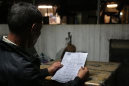 Fung, one of the rooftop dwellers, reads the eviction notice from the Buildings Department.