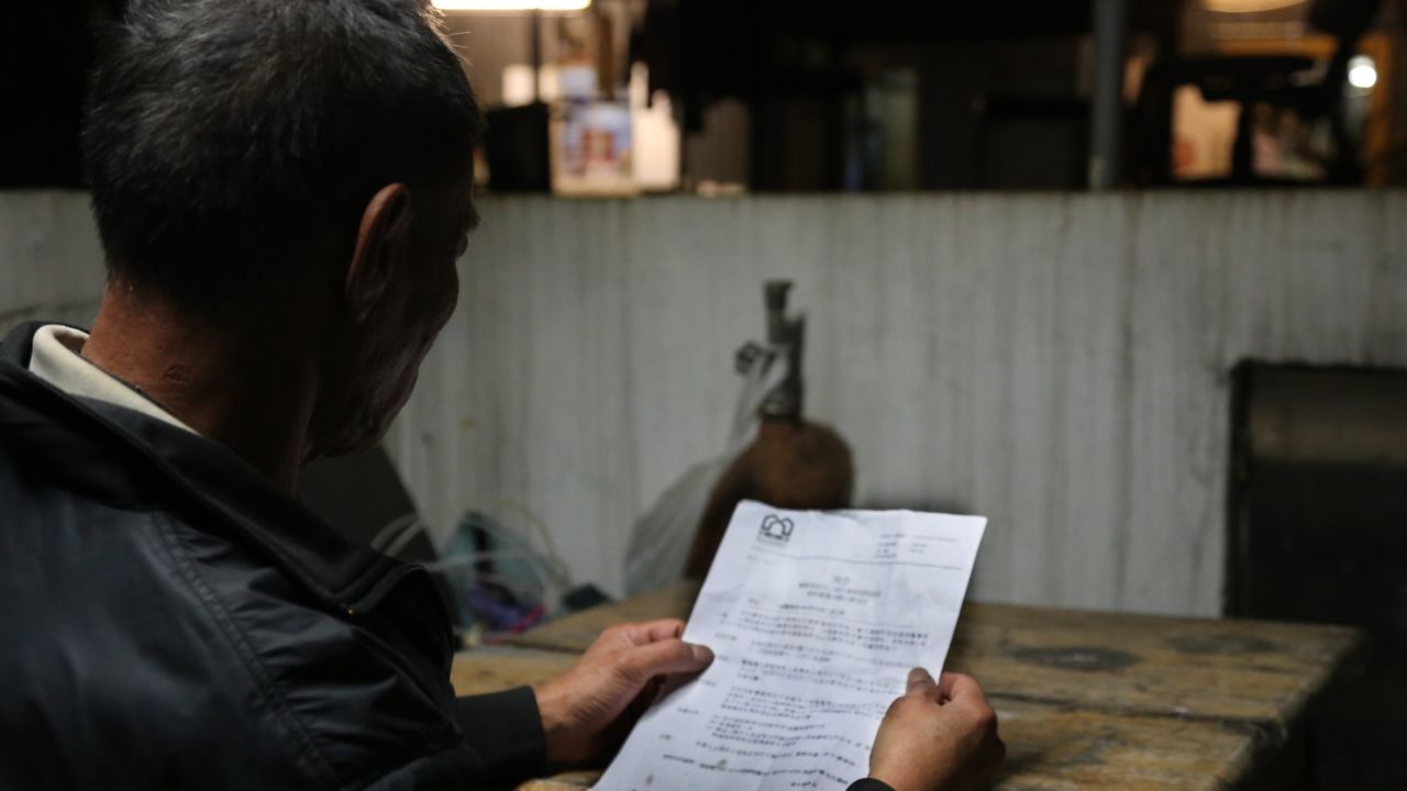 Fung, one of the rooftop dwellers, reads the eviction notice from the Buildings Department.