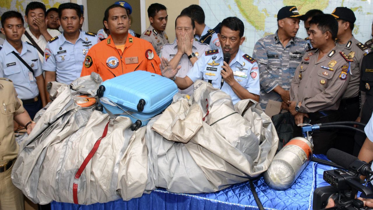 Indonesian air force personnel show debris, including a suitcase, that was found floating near the site where the AirAsia flight disappeared.