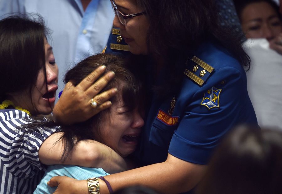 Family members of missing passengers react at an airport in Surabaya after watching news reports on December 30.