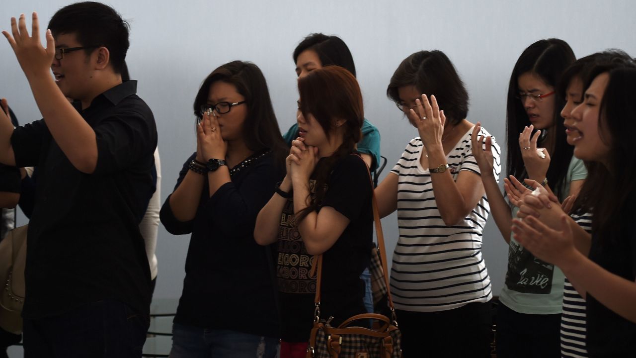 Relatives of passengers pray together inside a holding room at Juanda International Airport in Surabaya on December 31.