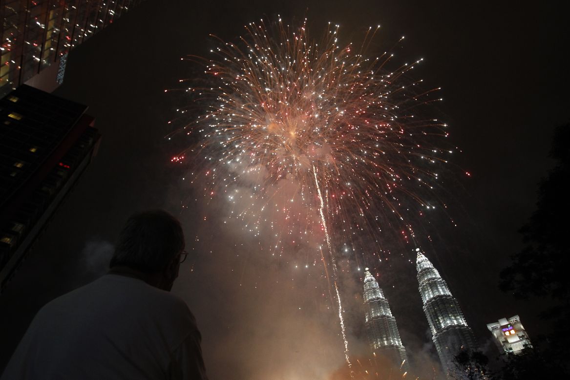 A man watches fireworks explode over Malaysia's landmark Petronas Towers during celebrations in Kuala Lumpur, Malaysia.