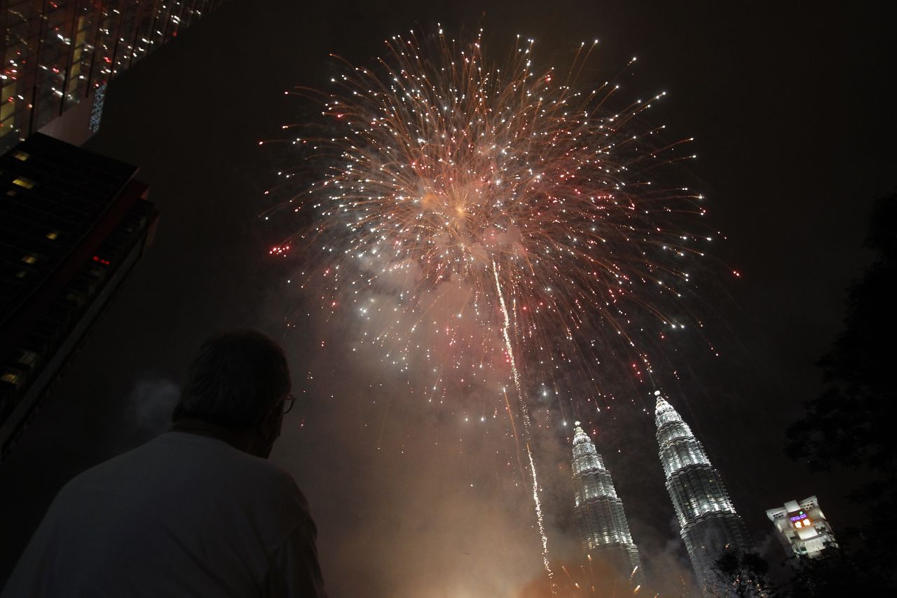 A man watches fireworks explode over Malaysia's landmark Petronas Towers during celebrations in Kuala Lumpur, Malaysia.