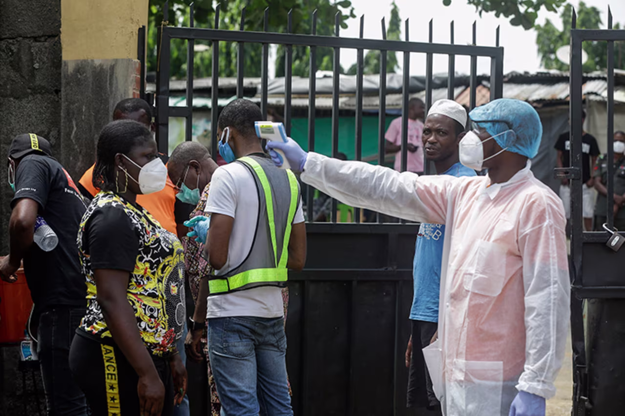 A health official, right, takes the temperature of a patient looking to be tested, before entering a government-run testing centre in Lagos, Nigeria, on Thursday, April 23.