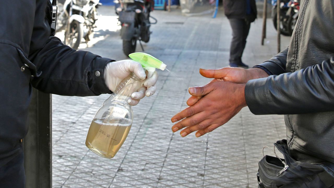 An Iranian man sprays alcohol on the hands of people outside an office building in Tehran on March 4.