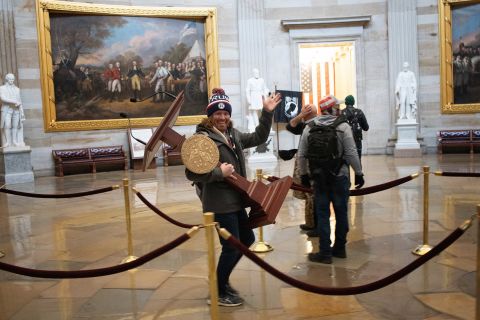 A pro-Donald Trump rioter, identified as Adam Johnson, carries the lectern of House Speaker Nancy Pelosi through the Capitol on January 6.