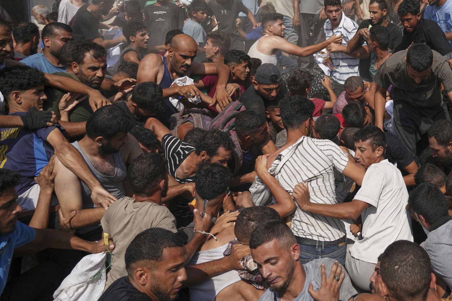 Palestinians struggle to collect humanitarian aid airdropped by parachutes into Gaza on Thursday, August 14.