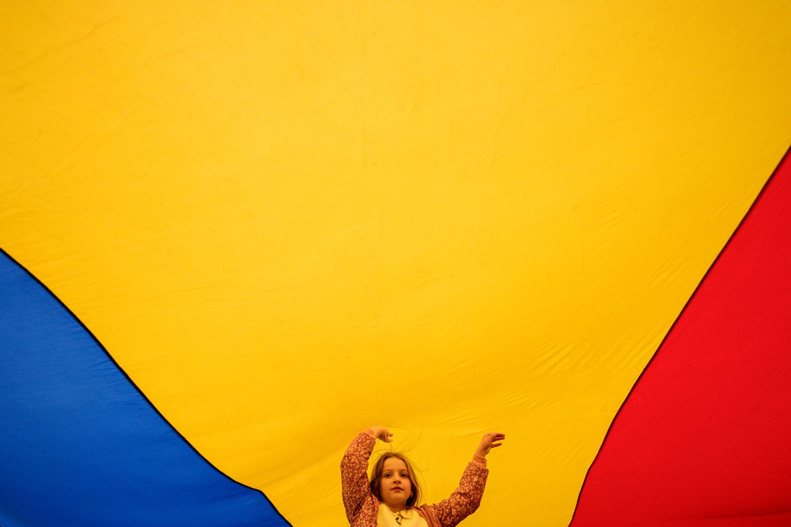A child plays under a large Romanian flag during a Pro-European Union rally in Bucharest, Romania, on Friday, May 9.