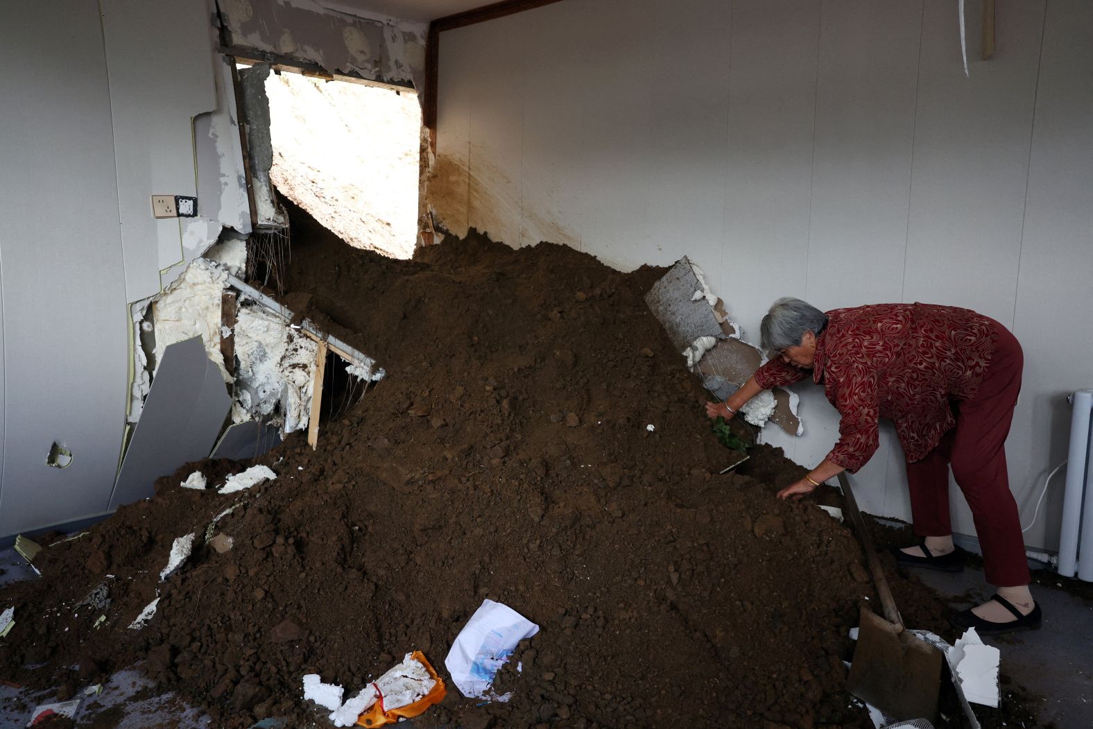 Guo Shuzhen shows a bed buried under debris as she speaks at an auto repair shop that was damaged by a landslide in Beijing on Monday, July 28. China is grappling with yet another deadly rainy season marked by extreme downpours, devastating floods and landslides. In recent days, <a href="index.php?page=&url=https%3A%2F%2Fwww.cnn.com%2F2025%2F07%2F28%2Fchina%2Fchina-beijing-rain-deaths-intl-hnk">intense rainstorms</a> have battered much of northern China.