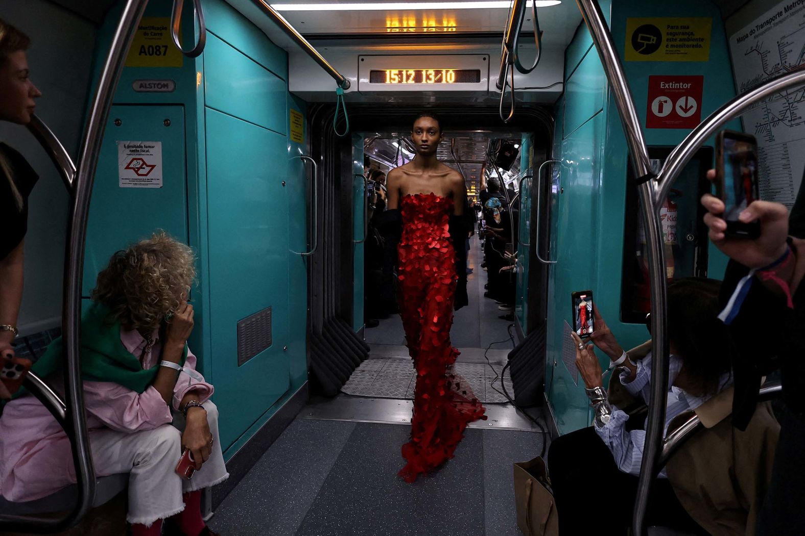 A model, wearing a creation by designer Gloria Coelho, passes by people on the subway during a fashion show in São Paulo, Brazil, on Monday, October 13. The subway was turned into a runway for the show.