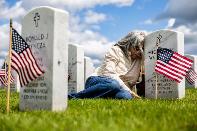 Rosie Weaver leans against the headstone of her husband, US Army Spc. Michael Weaver, after a Memorial Day ceremony in Holly Township, Michigan, on Sunday, May 25.