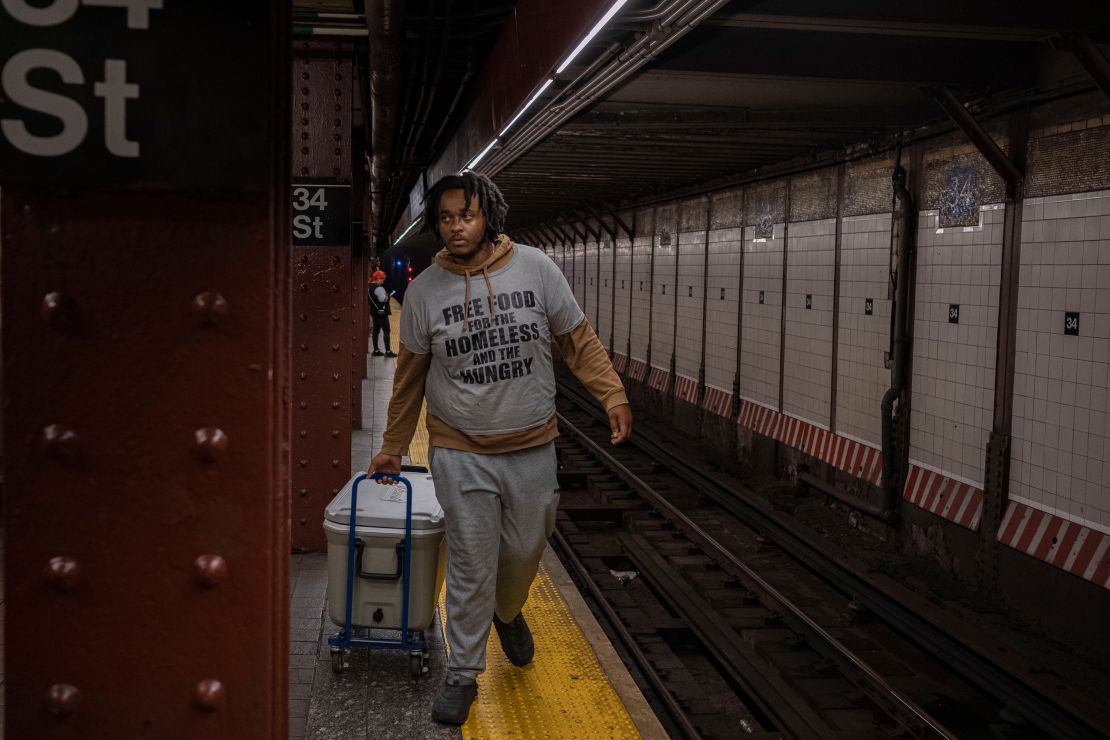 Carl Thomas pulls the cooler on a subway platform.