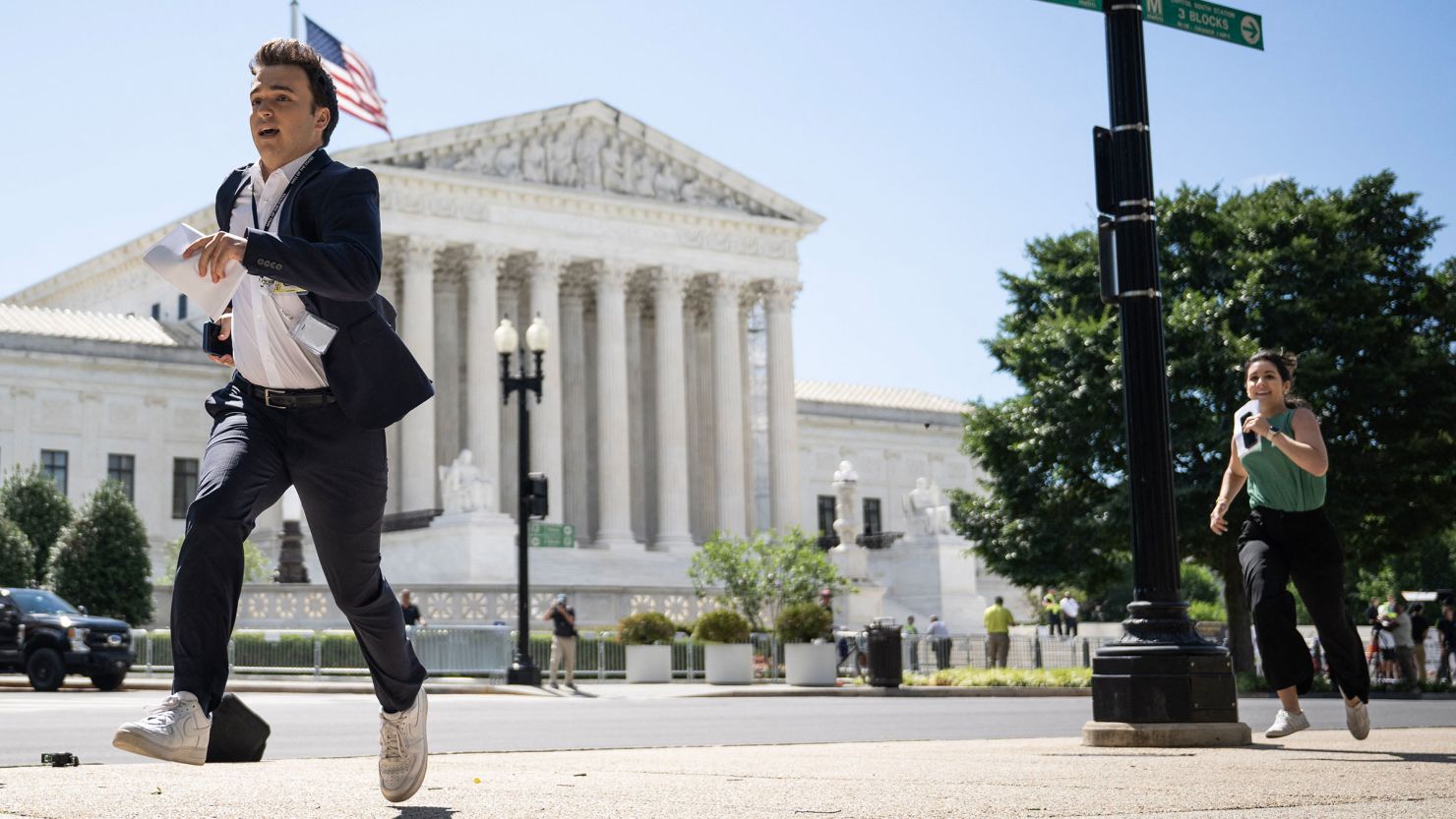 A journalist runs across the US Supreme Court plaza carrying an opinion to a news correspondent as the court handed down decisions on July 1, 2024, in Washington, DC.