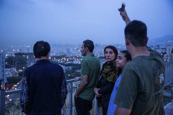 People look out at the skyline in Tehran after the airstrikes early on Friday.