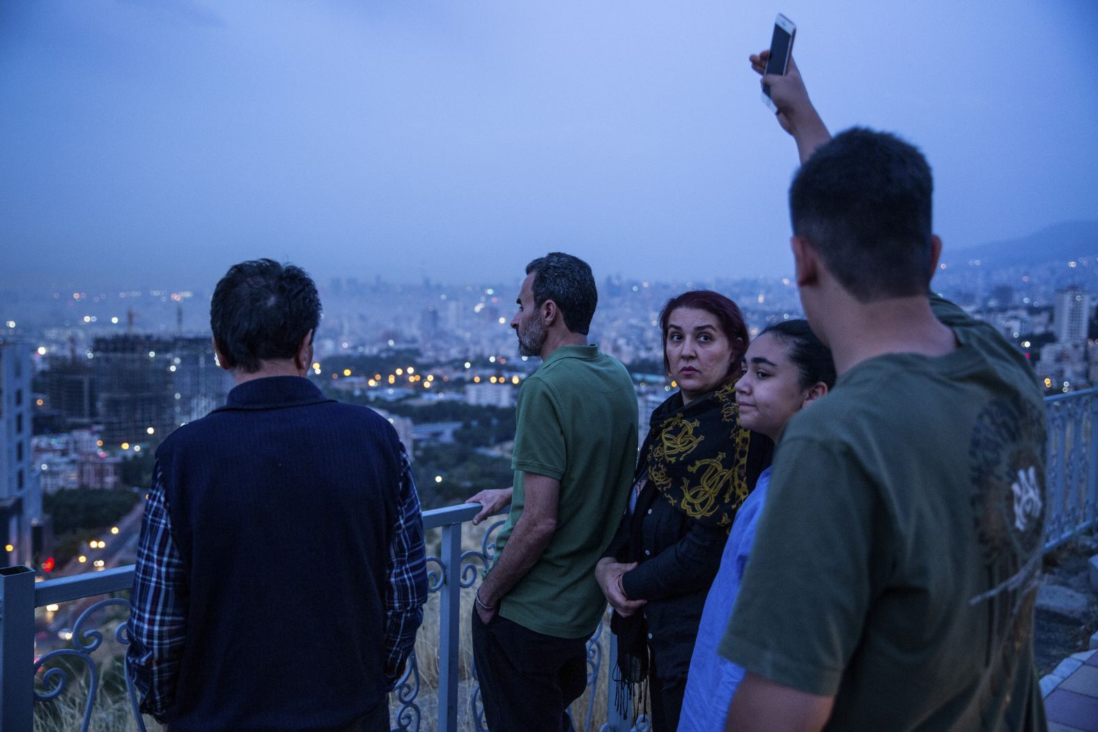 People look out at the skyline in Tehran after the airstrikes early on Friday.
