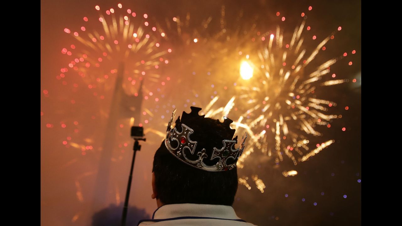A man watches as fireworks burst over the Manila suburb of Quezon City in the Philippines.