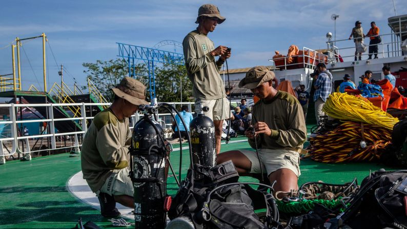 Marine divers prepare their gear on the deck of a ship before searching for passengers and debris January 1 at Kumai port in Pangkalan Bun.