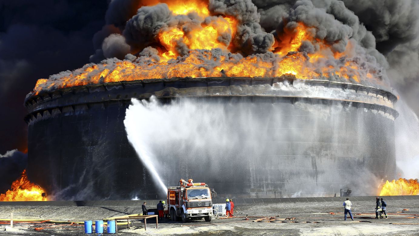 Firefighters spray water at an oil tank in Ras Lanuf, Libya, on Monday, December 29. Oil tanks at the Es Sider port caught fire after one was hit by a rocket during fighting between rival groups.