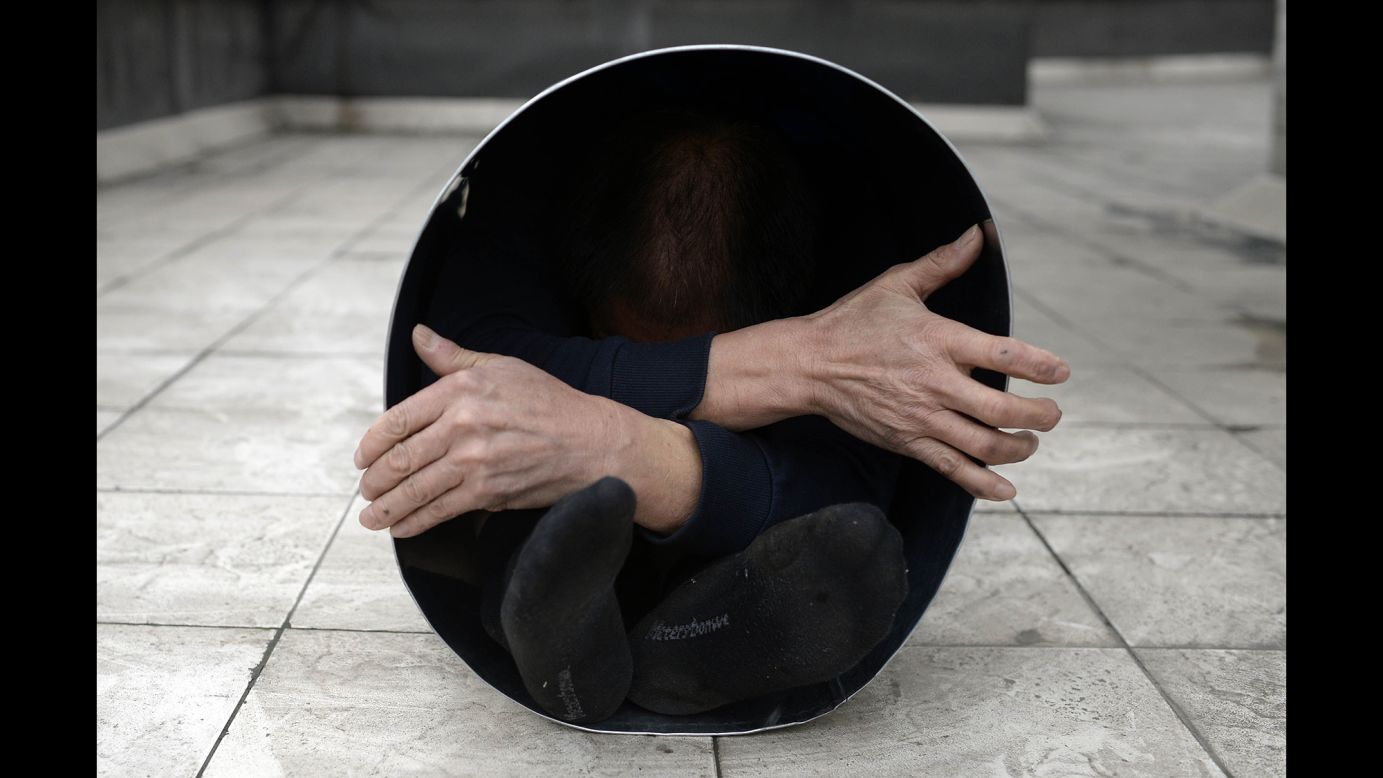 A man folds himself into a metal bucket in Chongqing, China, on Friday, December 26.