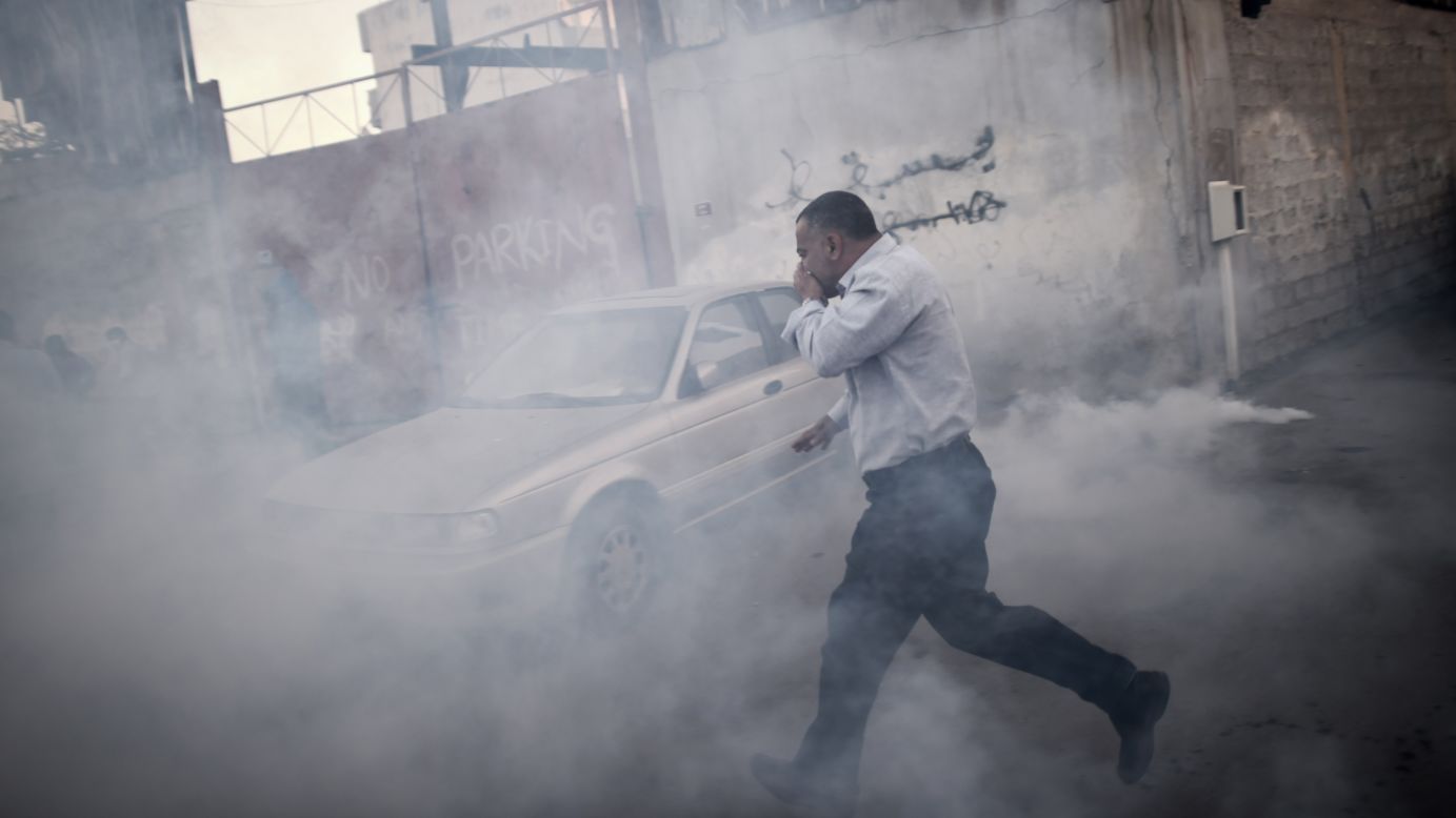 A man runs for cover from tear gas that was fired by police during clashes with protesters Tuesday, December 30, in Bilad al-Qadeem, Bahrain. The protest followed the arrest of Sheikh Ali Salman, leader of the banned Shiite opposition movement Al-Wefaq.