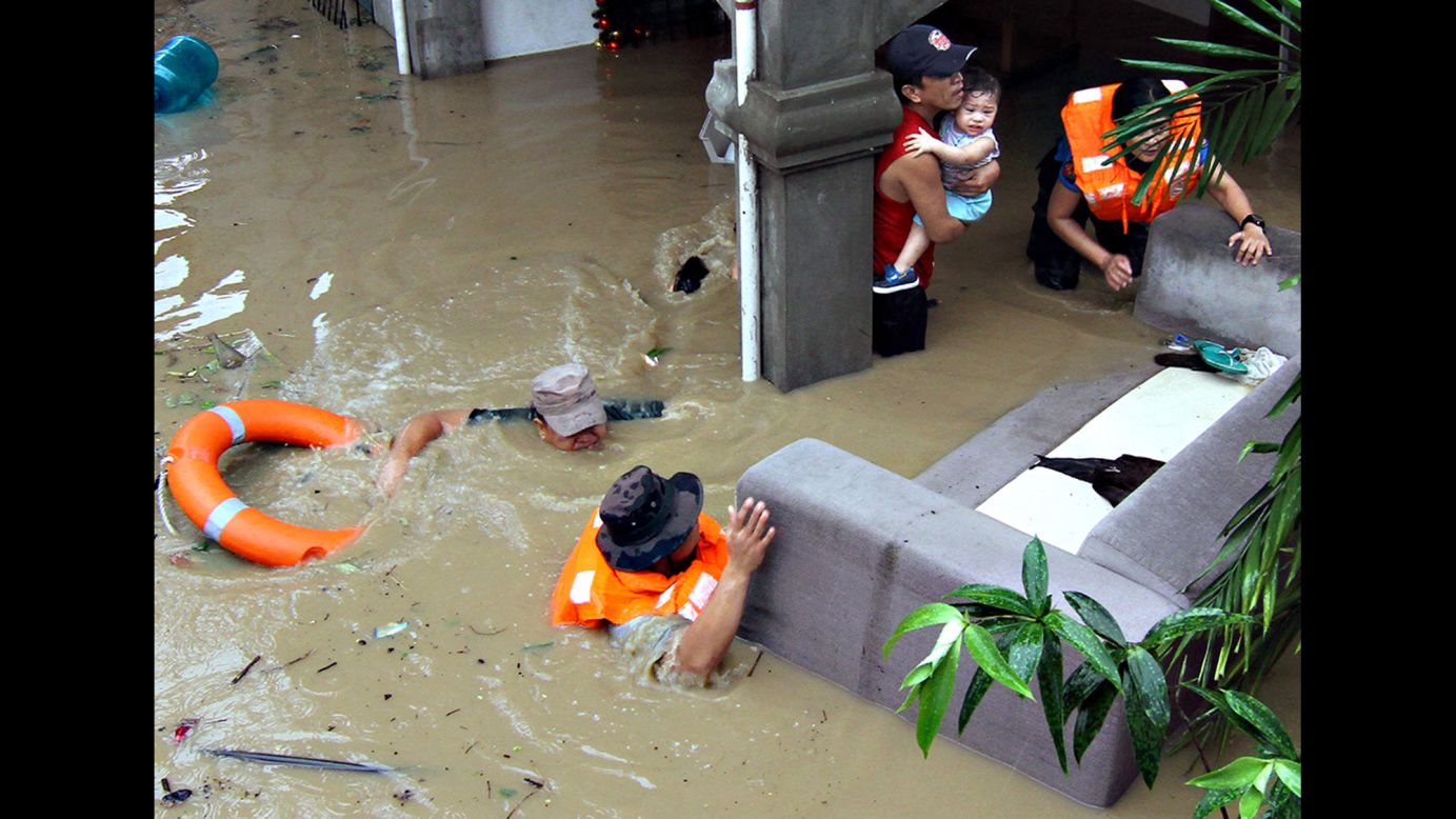 Police officers in Mindanao, Philippines, help families who were trapped in their homes during heavy flooding on Monday, December 29. The flooding was brought on by Tropical Storm Seniang.