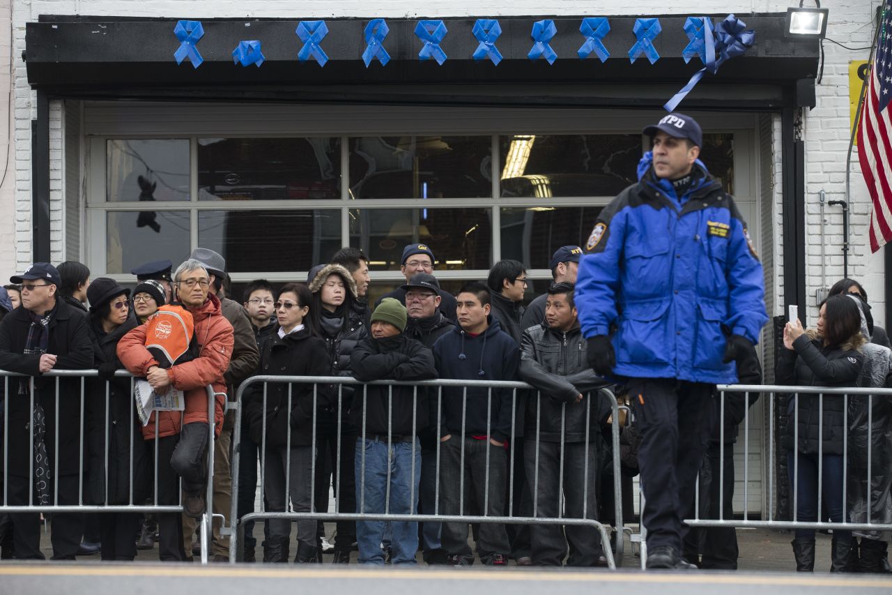 Onlookers gather at barricades before the funeral begins.