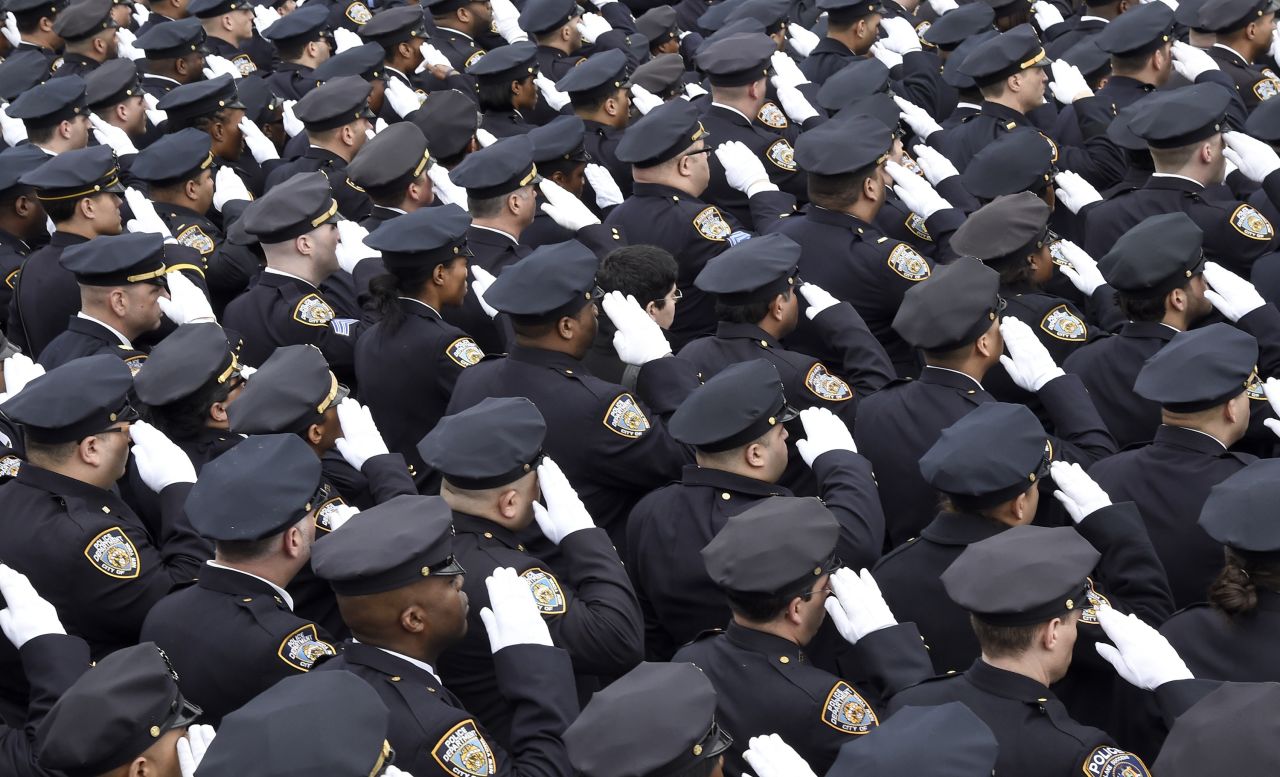 Police officers gathered for the funeral salute the fallen officer. 