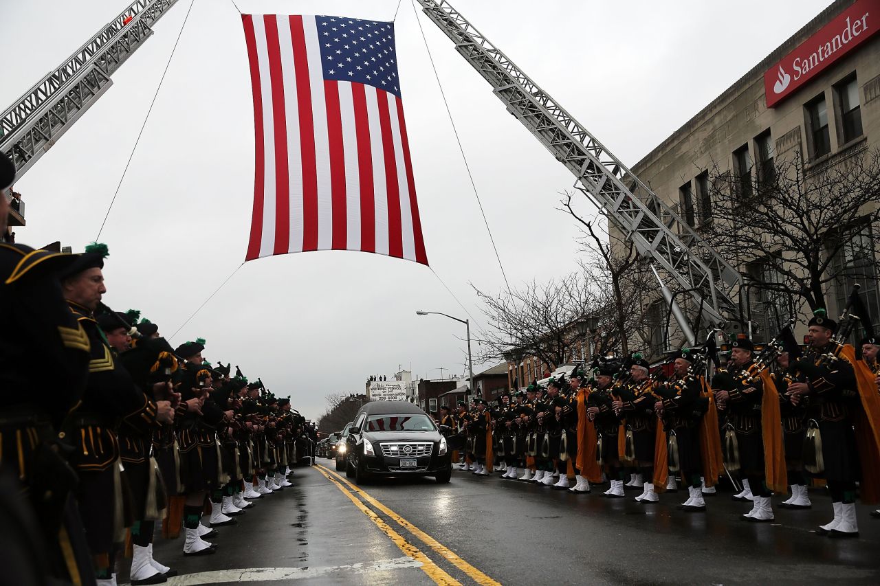 The hearse carrying Liu's body drives under a suspended American flag after the funeral. 