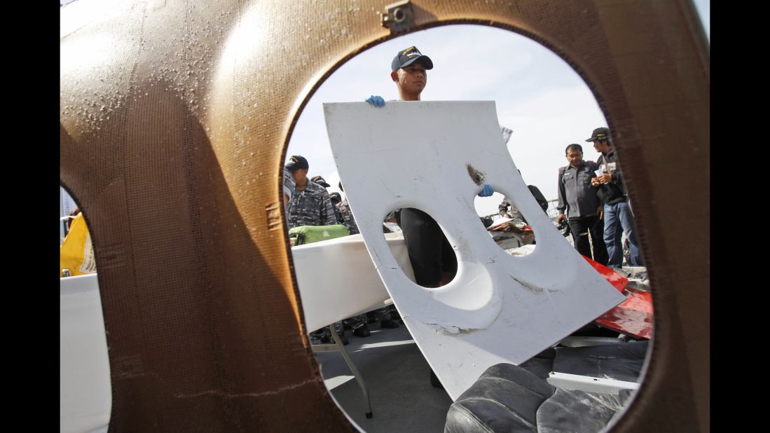 An Indonesian navy member holds a piece of window panel that was recovered during search operations.
