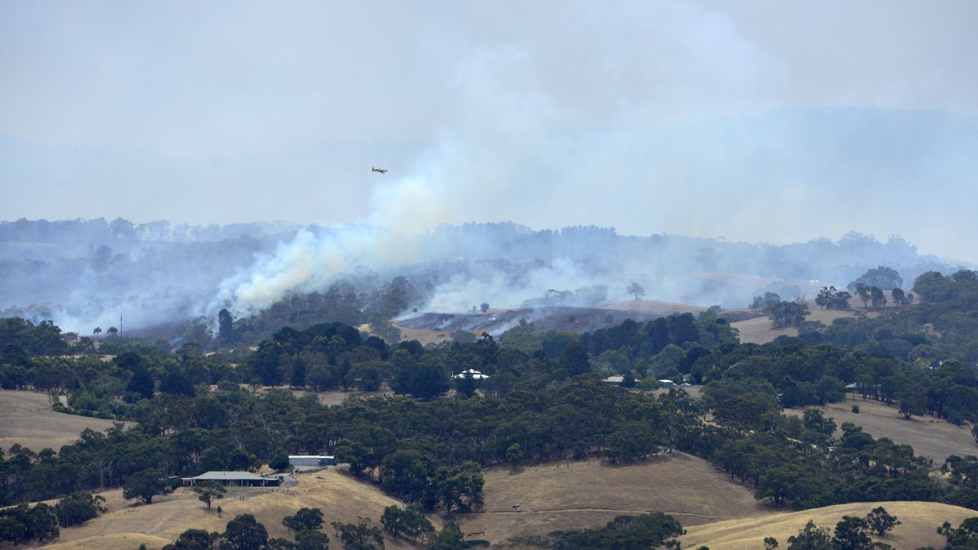 A plane flies over smoke from fires burning across Adelaide Hills in Australia over the weekend. Around nine towns in South Australia remain at risk.