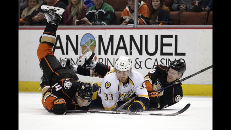 Nashville's Colin Wilson, center, falls to the ice along with Anaheim's Rene Bourque, left, and Ben Lovejoy during an NHL game Sunday, January 4, in Anaheim, California. The Ducks won 4-3 in overtime to improve their record to a league-best 26-9-6.