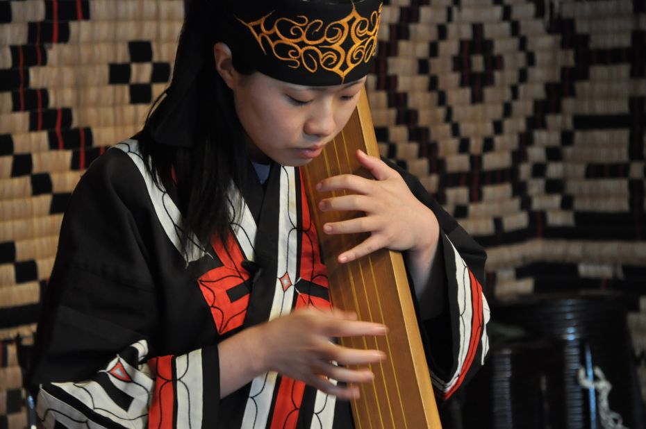A performer plays a traditional tonkori, a five-stringed instrument. Many of the place names in Hokkaido have a link to the Ainu language. The coastal town of Shiraoi where the Ainu Museum located means "land of many horseflies."  Sapporo is a derivation of the Ainu words for dry large river: "sat poro pet." 