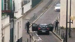 Armed gunmen face police officers near the offices of the French satirical newspaper Charlie Hebdo in Paris on January 7.