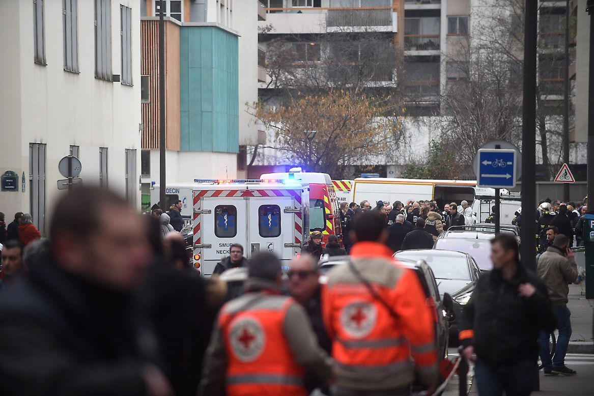 Ambulances and police officers gather in front of the building.