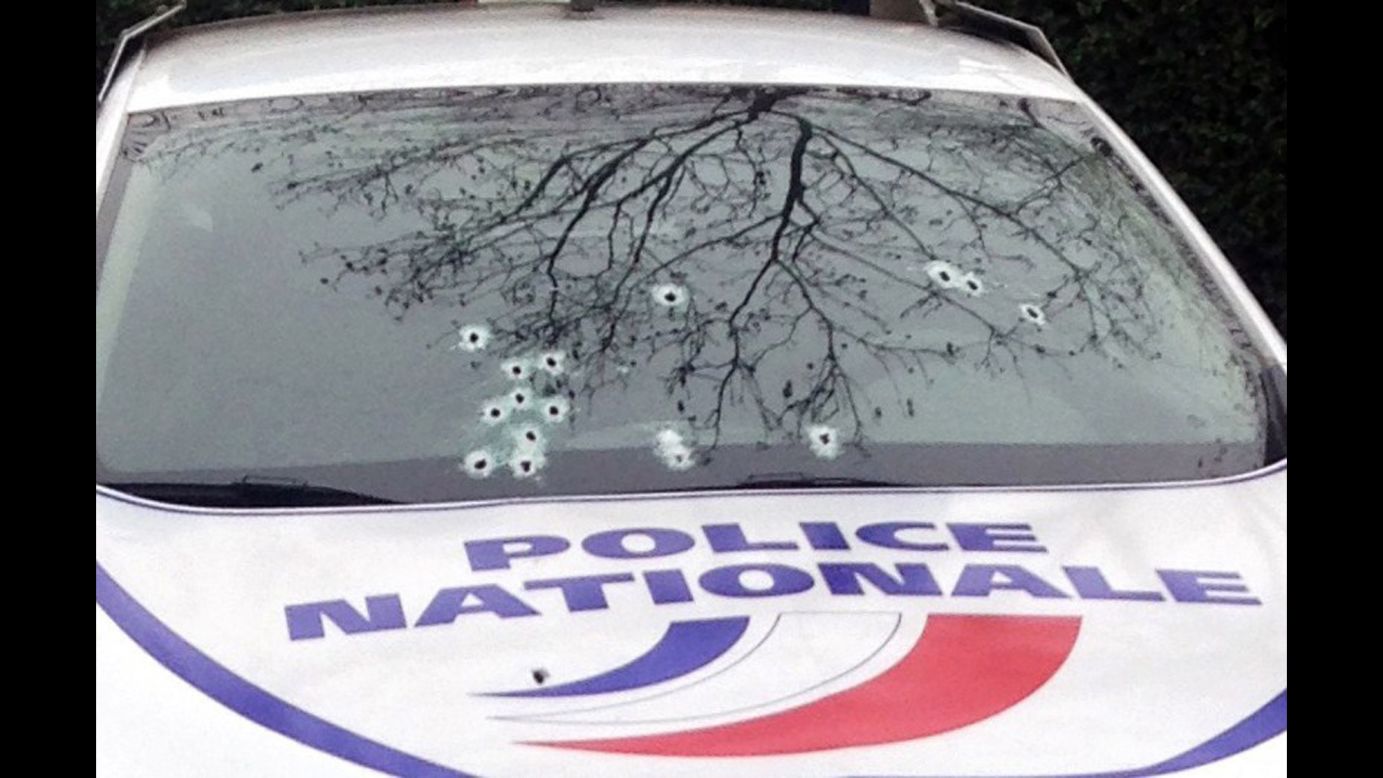 A police car sits riddled with bullets.