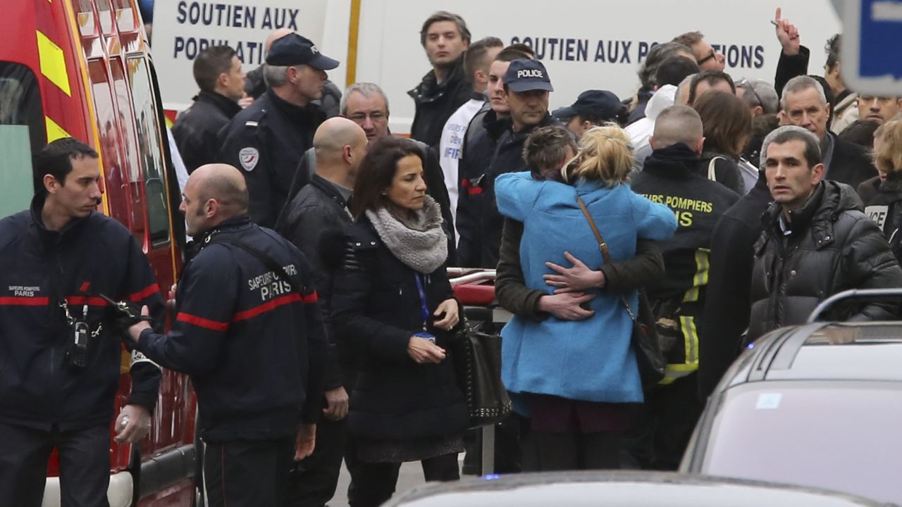 People hug each other outside the magazine's building after the attack.