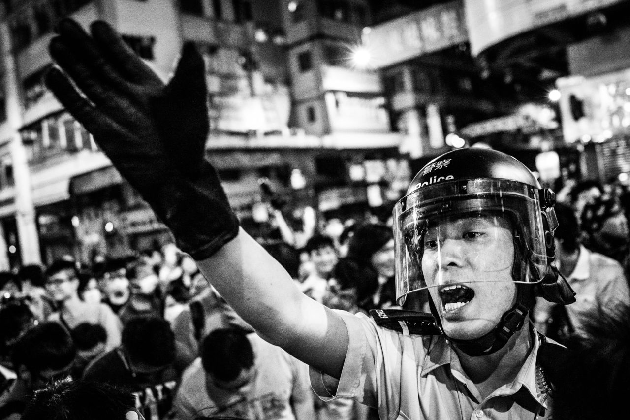 A policeman attempts to get protesters off the streets in Mong Kong, a gritty, working-class neighborhood. 