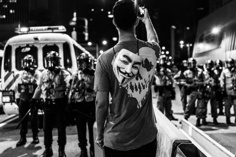 A protester snaps a photograph of Hong Kong policemen in riot gear with his smartphone. Bacani often moved to the front lines to document the Occupy protests. "It was the first time I saw this kind of passion," she said. "It gave this surreal vibe to the city." 