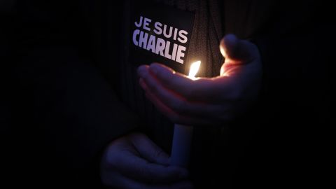 A man holds a candle and a sticker that translates to "I am Charlie" during a vigil in Paris on January 7.