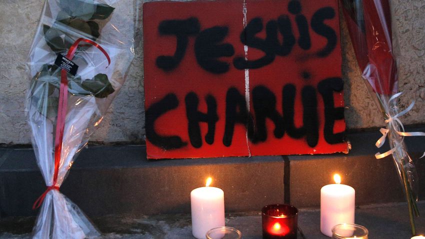 Flowers and candles are placed against a wall during a demonstration in Paris.