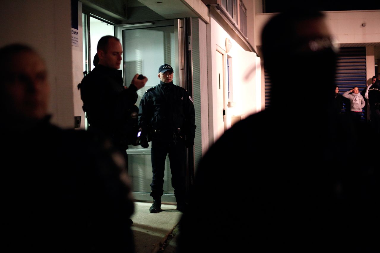 Police stand guard in front of an apartment building in the Croix-Rouge suburb of Reims, France, early on January 8. Forensics officers were looking for evidence related to the three suspects.