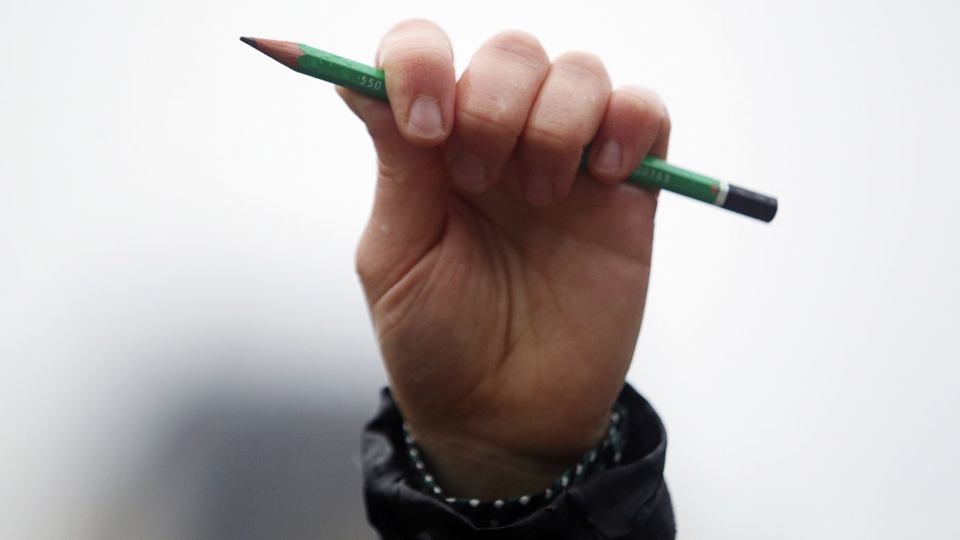 A man holds a pencil in front of Notre-Dame Cathedral during a moment of silence January 8 in the French capital. 