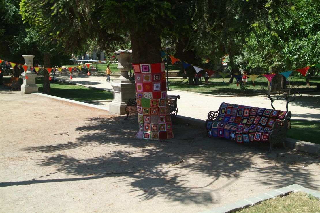 A yarn-bombed tree and bench add color to a park in central Santiago.