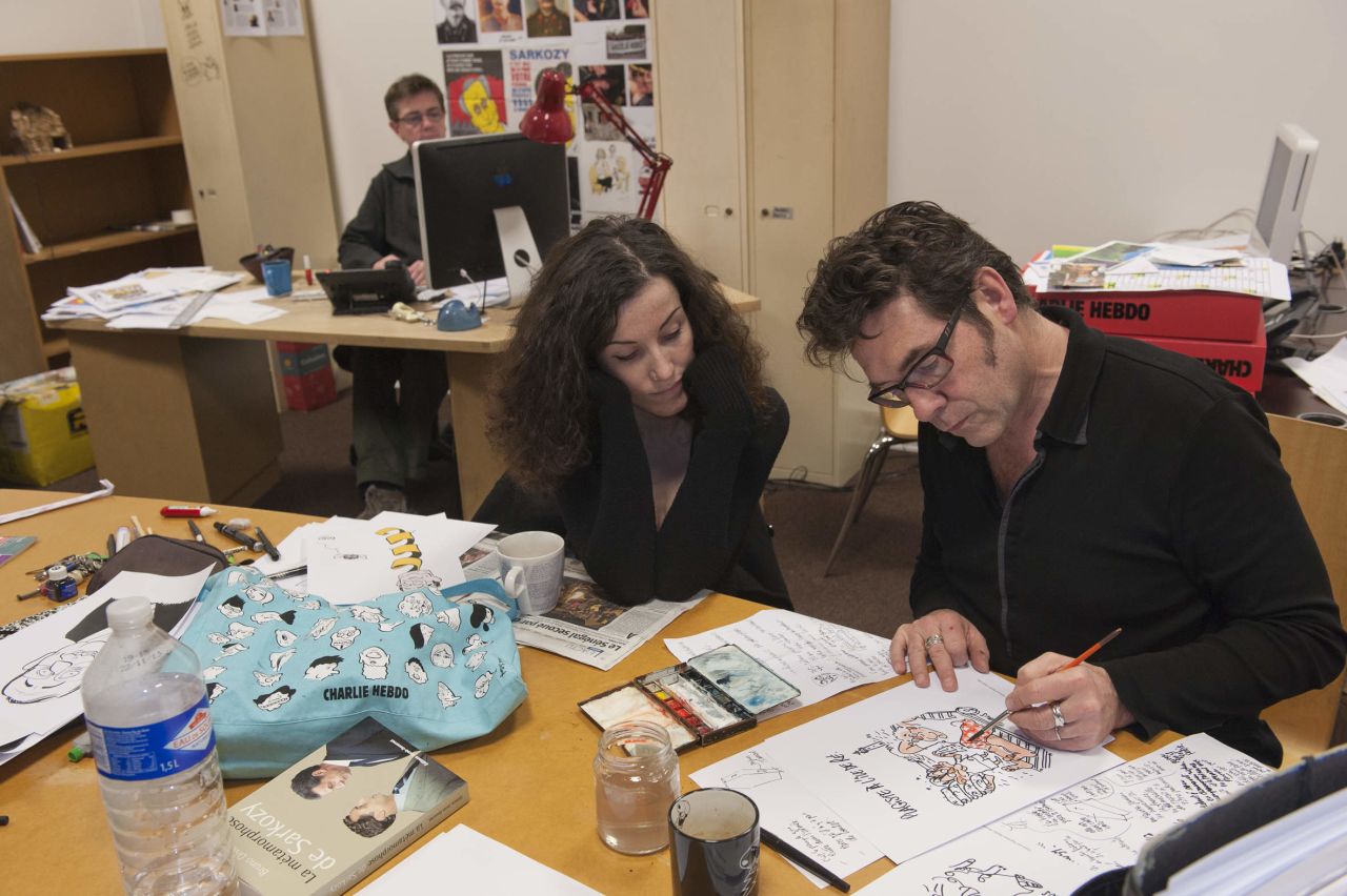 Verlhac sketches a political cartoon with Corinne Rey, a cartoonist also known as Coco, in 2012. Charbonnier is in the background. Rey said she took refuge under a desk <a href="http://www.cnn.com/2015/01/08/europe/charlie-hebdo-attack-timeline/" target="_blank">as her colleagues were killed.</a>
